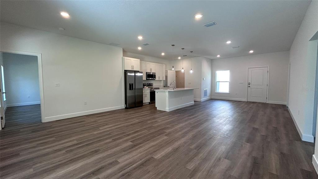 7191 Southwest 133rd Lane Ocala, FL 34473 - Photo 7 of 20 a view of a big room with wooden floor and a kitchen