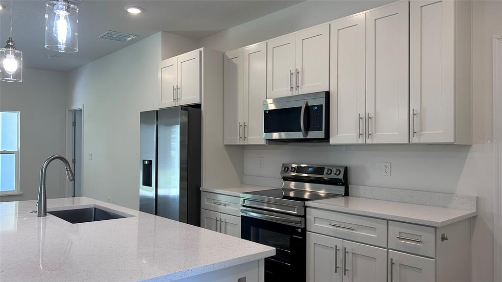 7191 Southwest 133rd Lane Ocala, FL 34473 - Photo 9 of 20 a kitchen with stainless steel appliances granite countertop a sink a stove and a refrigerator