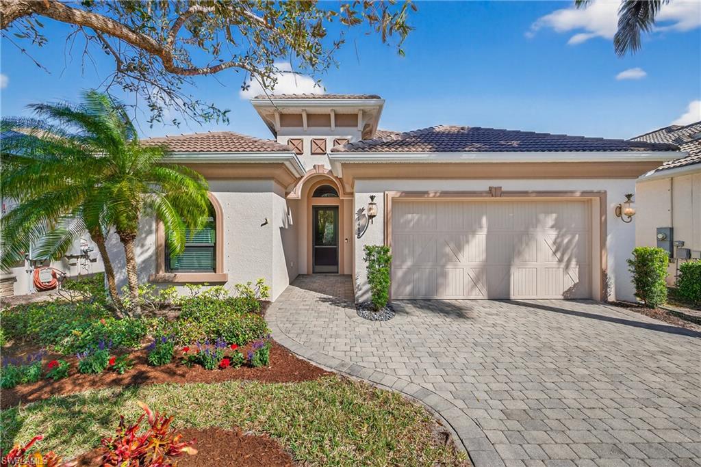 Naples Florida pool home with two-car garage, paver driveway, tile roof, and manicured landscaping in preferred X500 flood zone