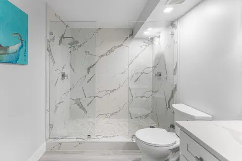 a white toilet sitting next to a shower