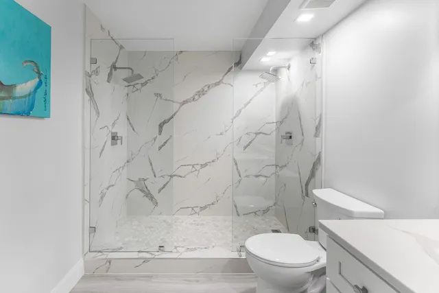 a white toilet sitting next to a shower