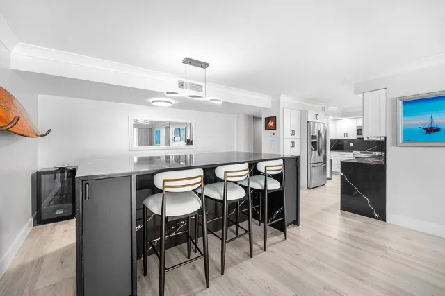 a kitchen with stainless steel appliances kitchen island granite countertop a dining table chairs and a refrigerator