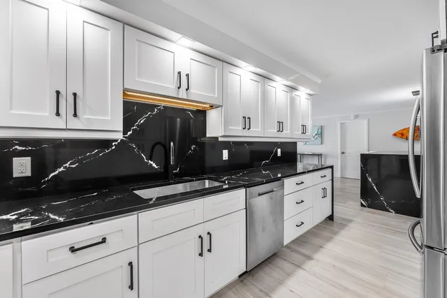 a kitchen with granite countertop a sink stainless steel appliances and cabinets