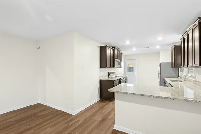 a large kitchen with a sink and dishwasher a stove with wooden floor