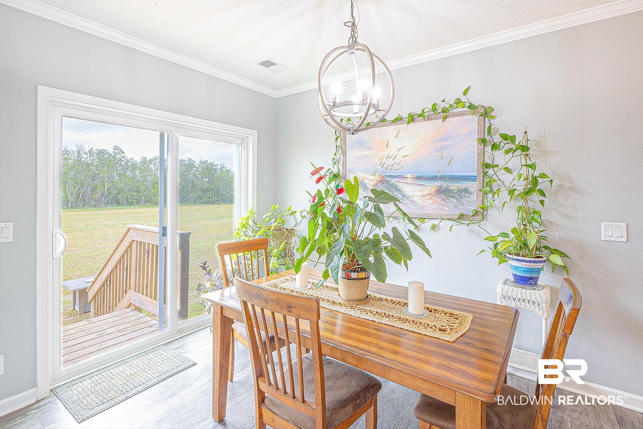 16000 John Bauer Road Summerdale, AL 36580 - Photo 16 of 34 Dining space with a notable chandelier, wood finished floors, visible vents, baseboards, and crown molding