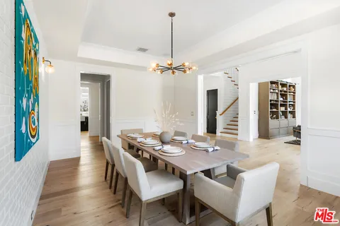 a view of a dining room and livingroom with furniture wooden floor a chandelier