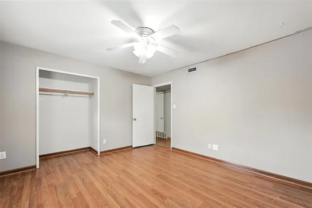an empty room with wooden floor and fan