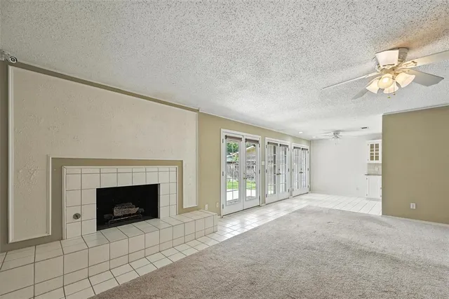 a view of an empty room with a fireplace and a fan