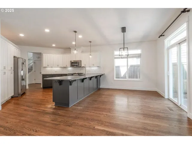 a kitchen with kitchen island granite countertop a sink cabinets and stainless steel appliances