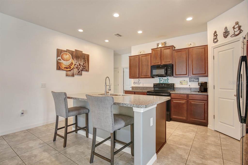 12618 Sandpine Reserve Place Gibsonton, FL 33534 - Photo 7 of 28 a kitchen with a refrigerator a stove top oven and a center island