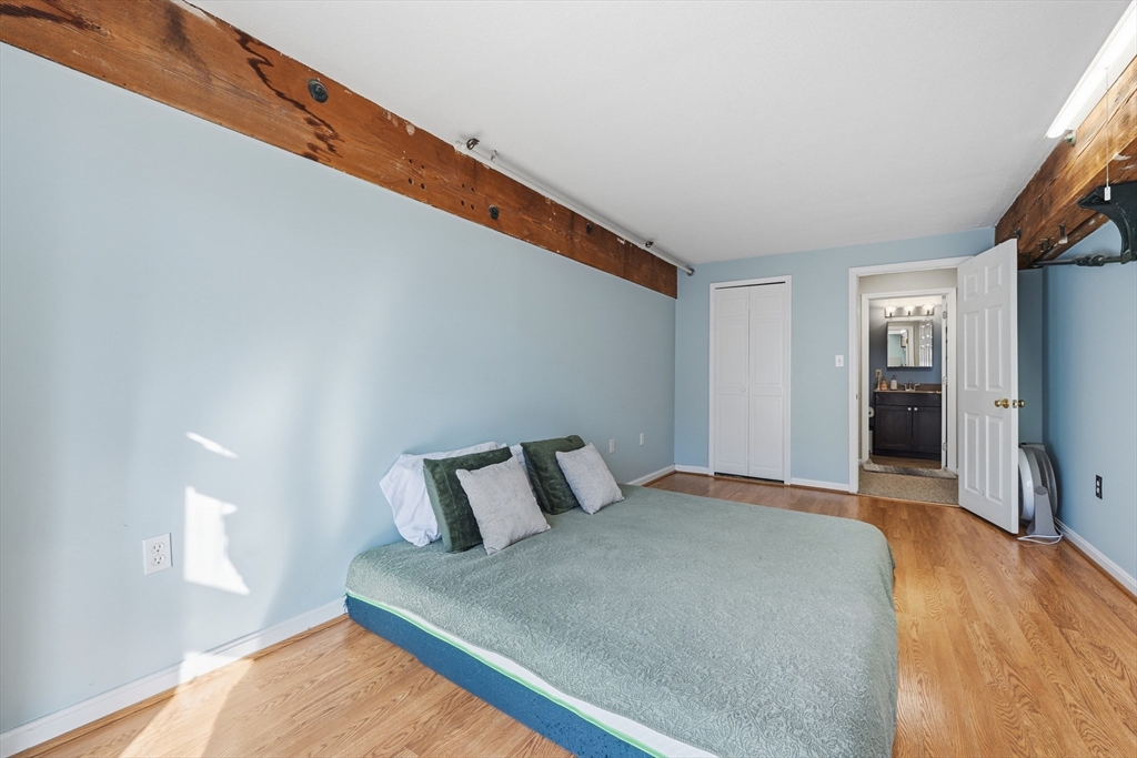 200 Market Street, Unit 217 Lowell, MA 01852 - Photo 18 of 38 a bedroom with a bed and a flat tv screen on wall
