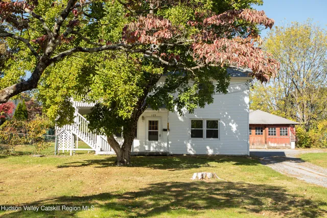a front view of a house with a tree