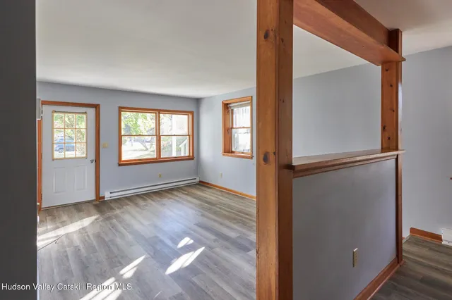 an empty room with wooden floor mirror and windows