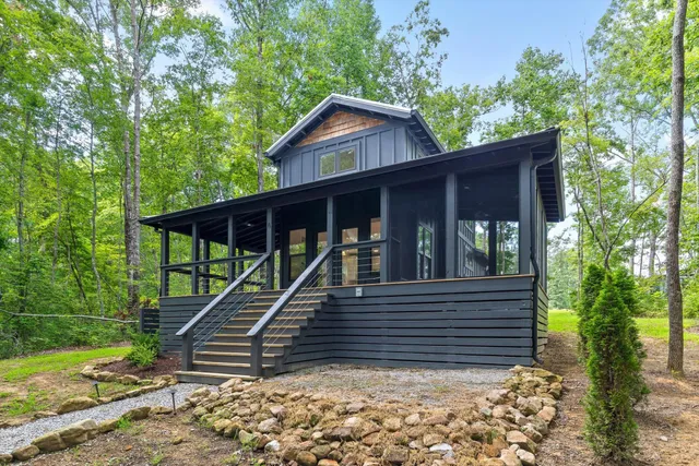 a view of wooden house with a yard and large trees