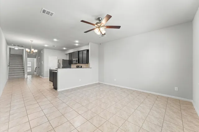 a view of an empty room with a chandelier fan