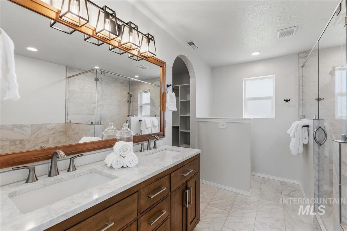 12310 West Hidden Point Drive Star, ID 83669 - Photo 5 of 48 Dual vanity with undermount sinks and brushed nickel faucets, set in a wood-finish cabinet with a light-toned countertop