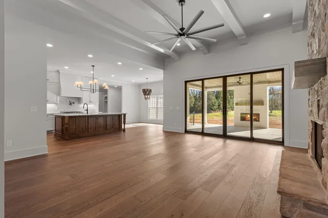 a large white kitchen with a refrigerator a kitchen island a stove and a wooden floors
