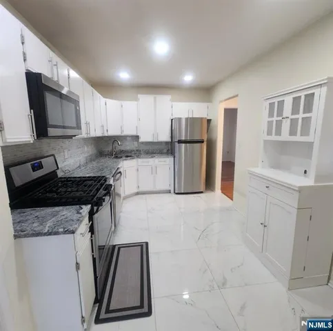 a kitchen with a refrigerator sink and white cabinets