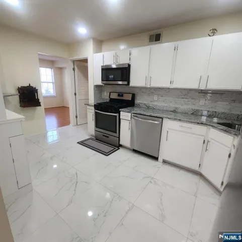 a kitchen with granite countertop white cabinets and stainless steel appliances