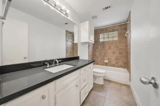 a bathroom with a granite countertop sink a toilet a mirror and shower