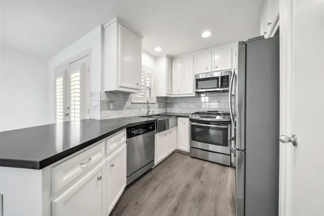 a kitchen with stainless steel appliances granite countertop a stove a sink and white cabinets