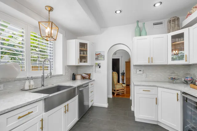 a kitchen with white cabinets a sink dishwasher and a stove