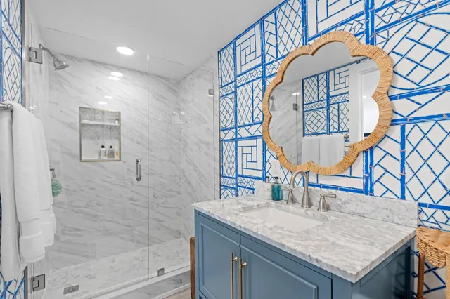a bathroom with a granite countertop sink a mirror and shower