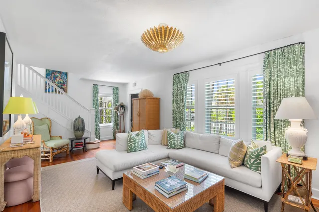 a living room with furniture a rug a lamp and a large window