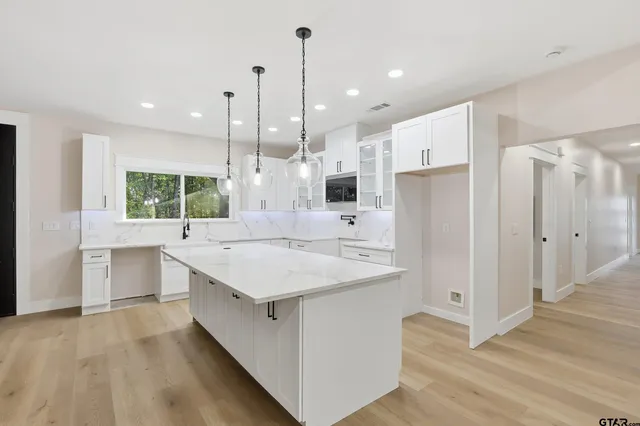 a large white kitchen with kitchen island a sink stainless steel appliances and cabinets