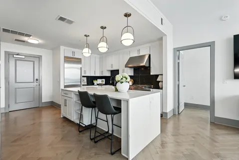 a kitchen with stainless steel appliances a dining table chairs stove and cabinets
