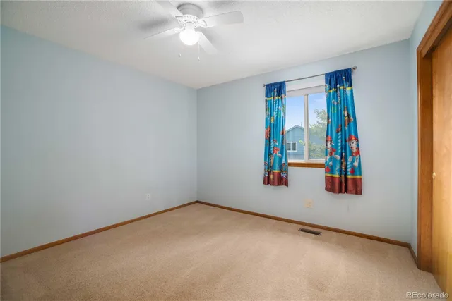 an empty room with windows and ceiling fan view