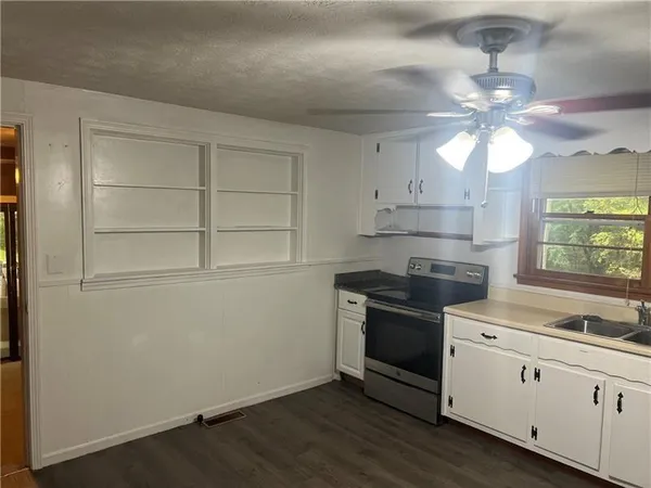 a kitchen with granite countertop a stove a sink and a refrigerator