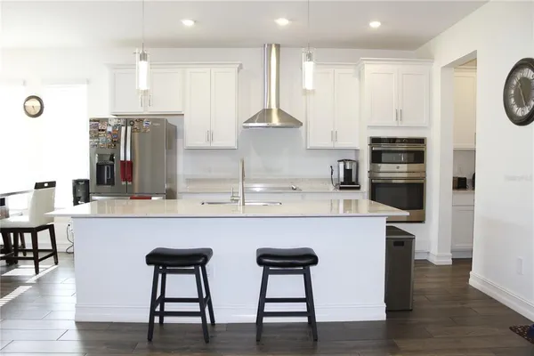 a kitchen with stainless steel appliances a dining table chairs and refrigerator