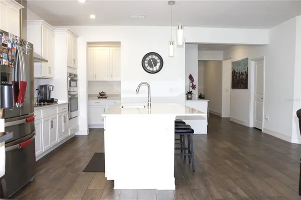 a very nice looking room with a large window wooden floor and white cabinets
