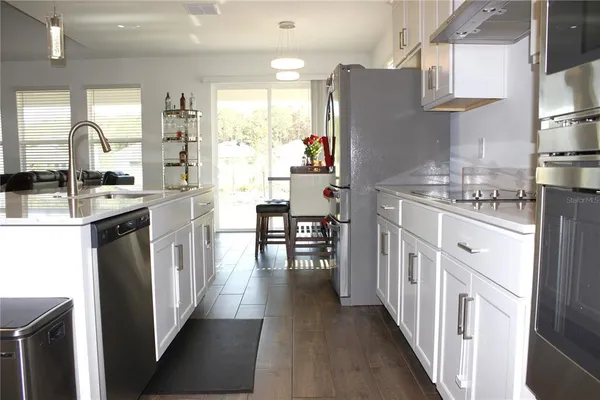 a kitchen with stainless steel appliances granite countertop a refrigerator oven a sink dishwasher and white cabinets with wooden floor