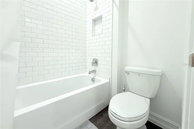 a white toilet sitting next to a bathtub