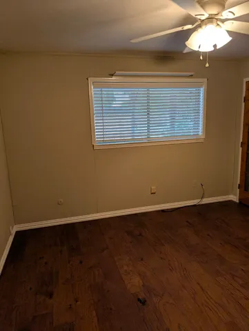 a view of an empty room with wooden floor and a chandelier fan