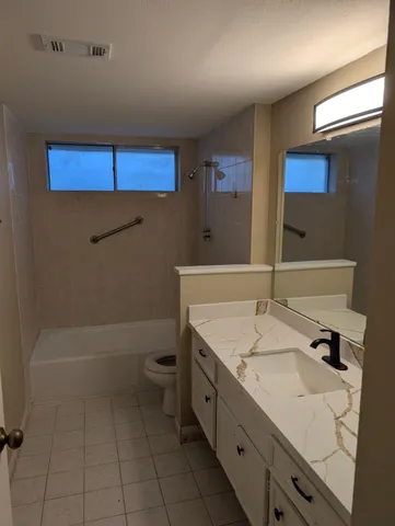 a bathroom with a granite countertop sink a toilet and bathtub