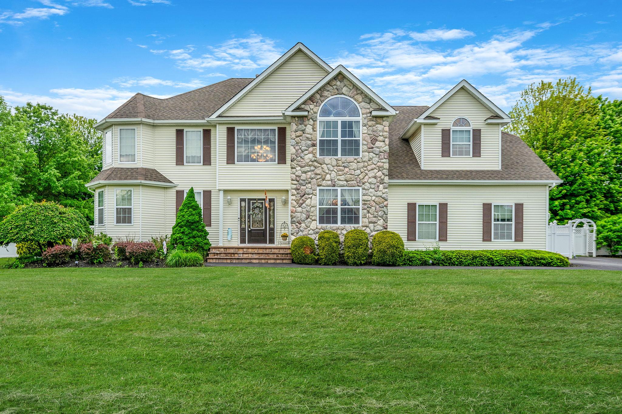 View of front of home featuring a shingled roof, a front lawn, and stone siding