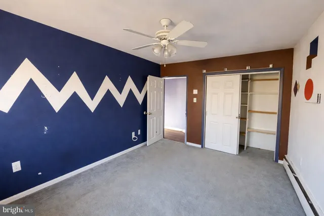 an empty room with closet and a ceiling fan