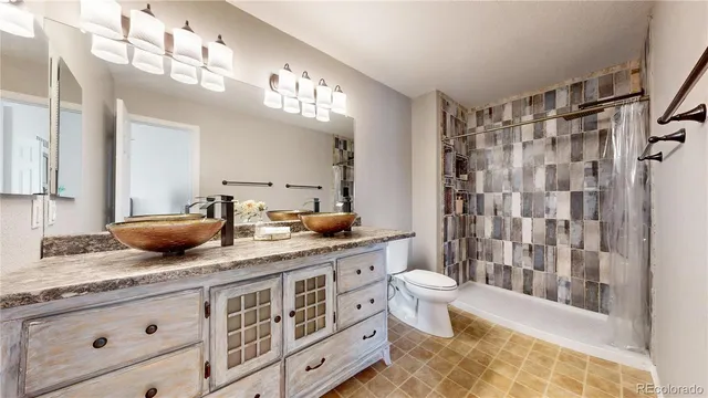 a spacious bathroom with a granite countertop sink a toilet a mirror a bathtub and shower