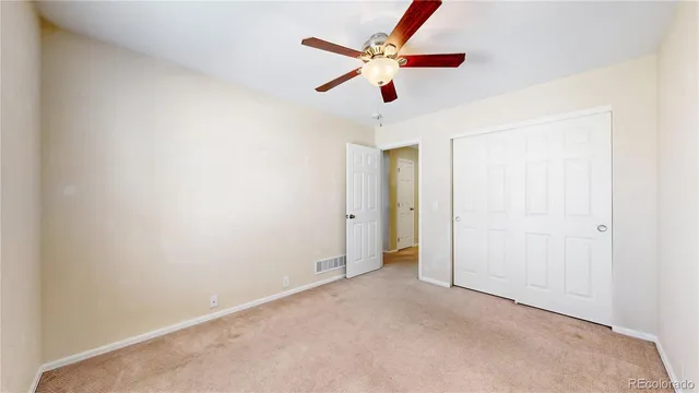 an empty room with ceiling fan and window