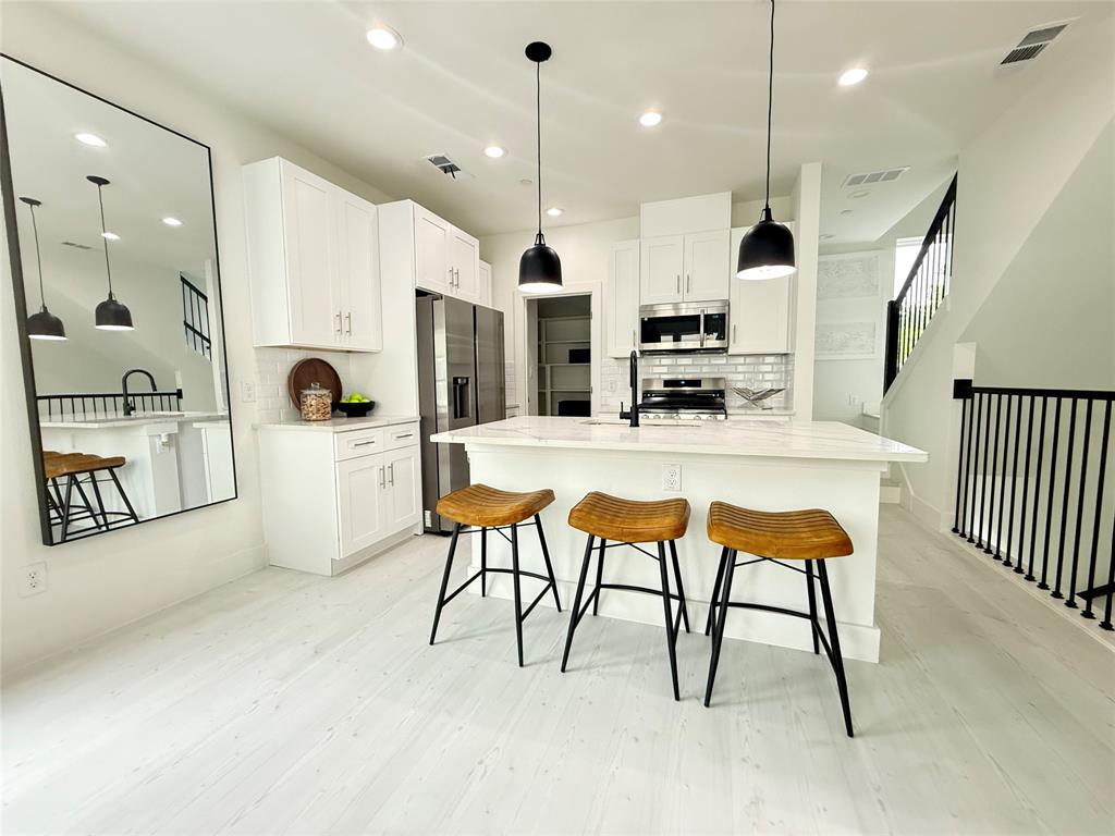 a kitchen with stainless steel appliances kitchen island granite countertop a stove a sink and a refrigerator