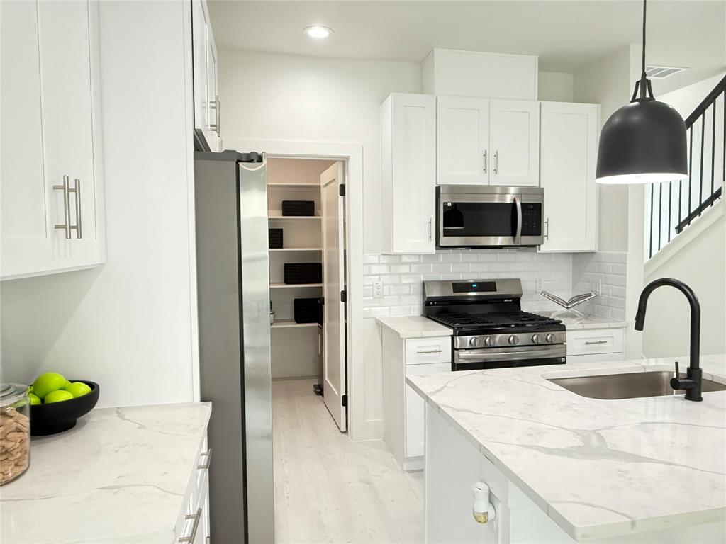 7207 Mohawk Drive, Unit 303 Dallas, TX 75235 - Photo 9 of 23 a kitchen with stainless steel appliances a stove a sink a microwave a refrigerator and cabinets