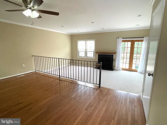 an empty room with wooden floor fan and windows