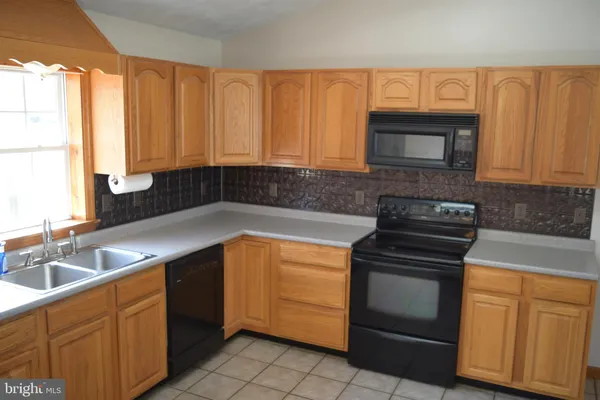 a kitchen with granite countertop a sink stove and cabinets