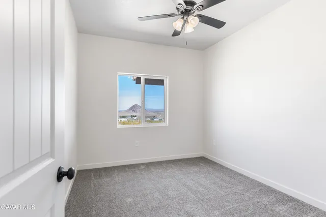 an empty room with a window and ceiling fan
