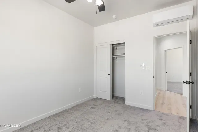an empty room with closet and a chandelier fan
