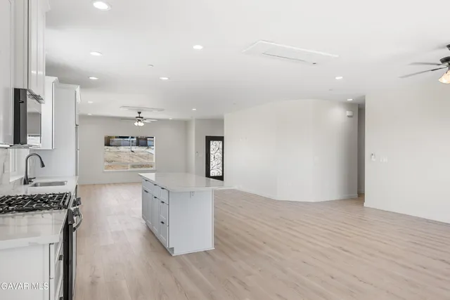 a view of a kitchen with kitchen island a sink wooden floor and stainless steel appliances