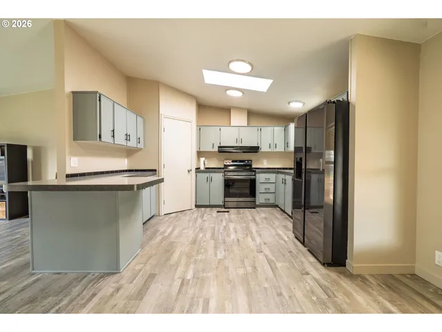 a kitchen with stainless steel appliances granite countertop a refrigerator a stove top oven and a sink
